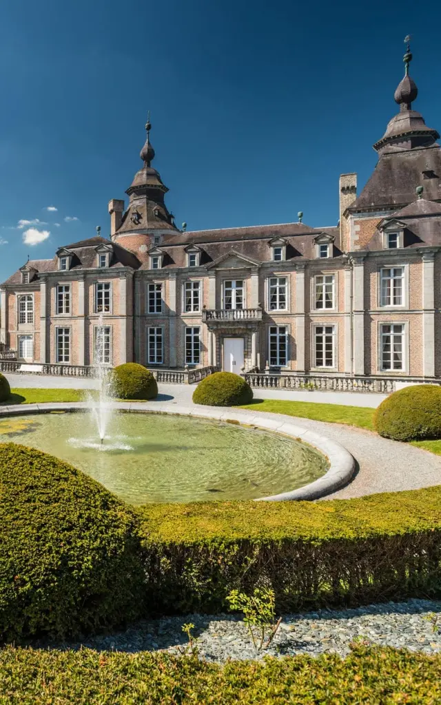Jardin à la française avec allées sinueuses et buissons taillés devant le château de Modave